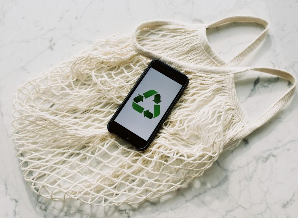pexels-photo-3850512-3850512 Overhead of smartphone with simple recycling sign on screen placed on white eco friendly mesh bag on marble table in room